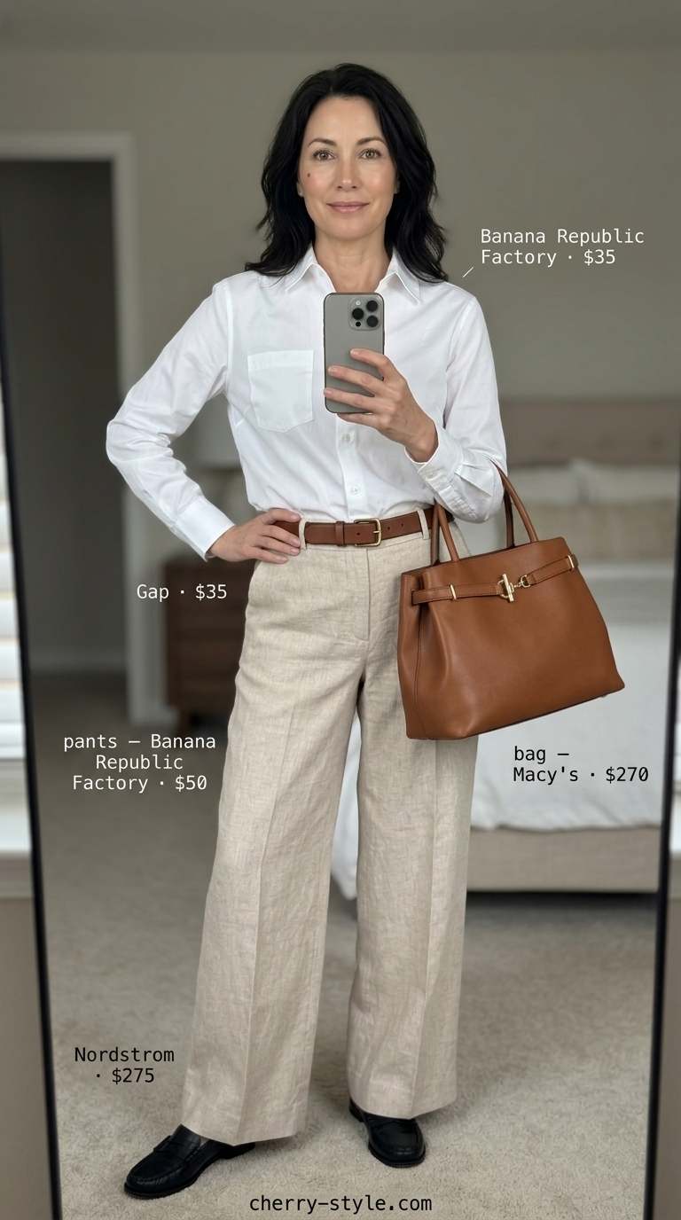 Classic summer outfit for women over 50 2026: Beige trousers, white shirt, and navy loafers for sophisticated office wear.