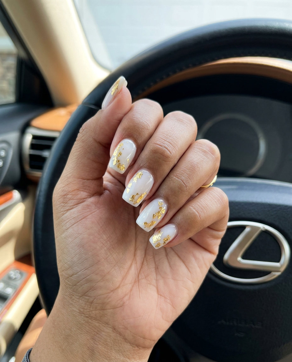 Elegant tropical nail designs 2026: Golden hour shimmer with milky white base and scattered gold foil for special events.